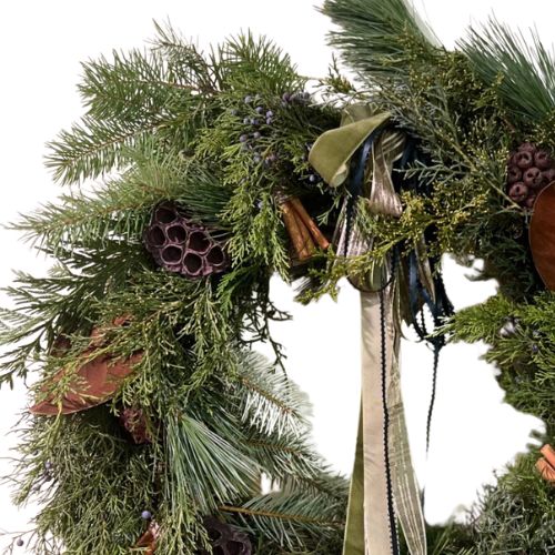 Decorative wreath with greenery, ribbons, and natural elements on a white background