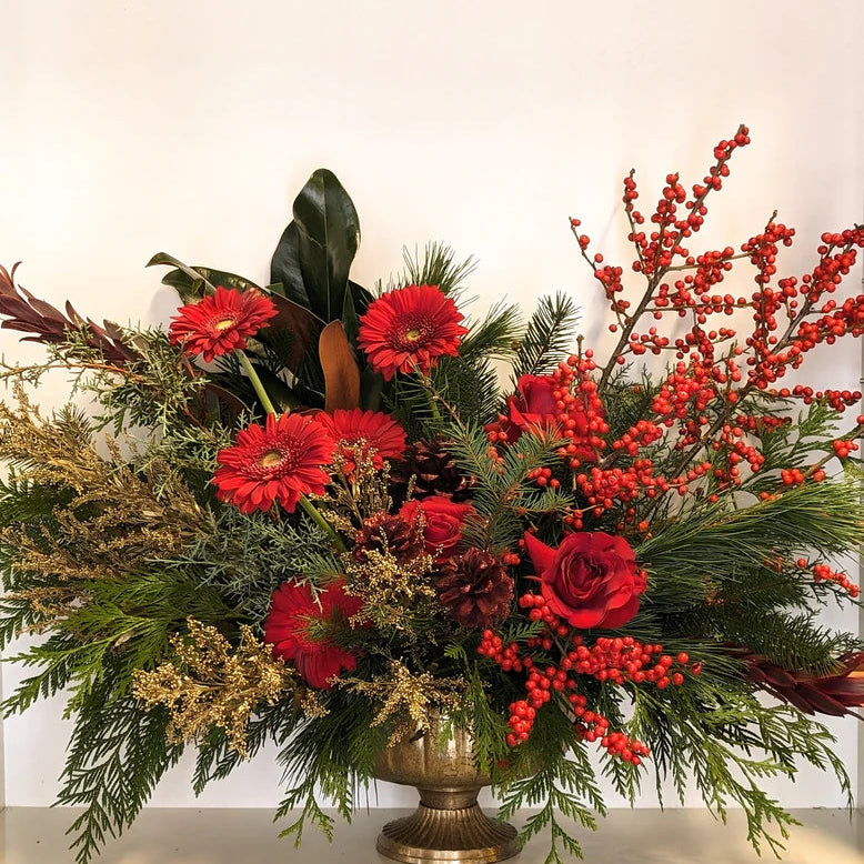 Decorative floral arrangement with red flowers and greenery on a white background