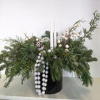 MacRose Design Co. Decorative arrangement with greenery, berries, and a candle on a white surface.