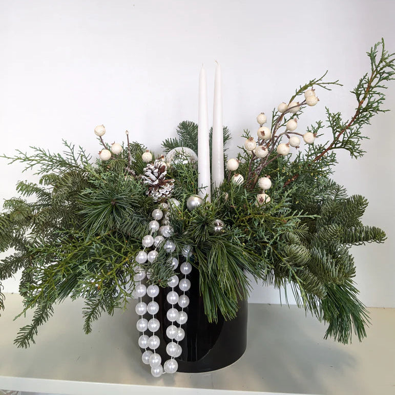 MacRose Design Co. Decorative arrangement with greenery, berries, and a candle on a white surface.